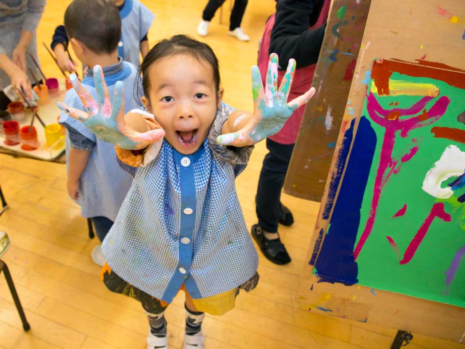 写真:手を絵具だらけにして絵を描く園児